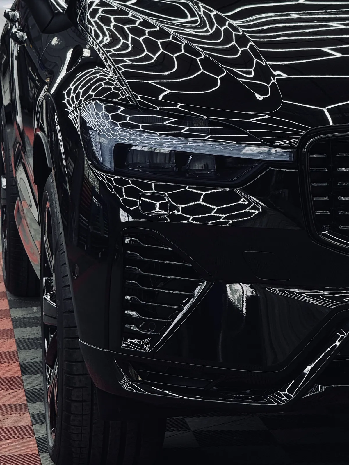 Mustan Volvo XC60:n etupuskuri ja ajovalo lähikuvassa